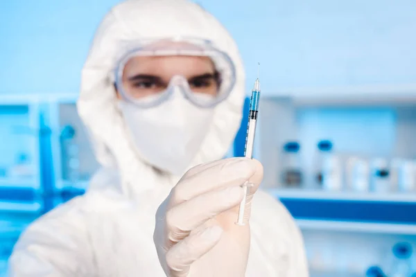 Selective focus of syringe with vaccine in hand of scientist — Stock Photo