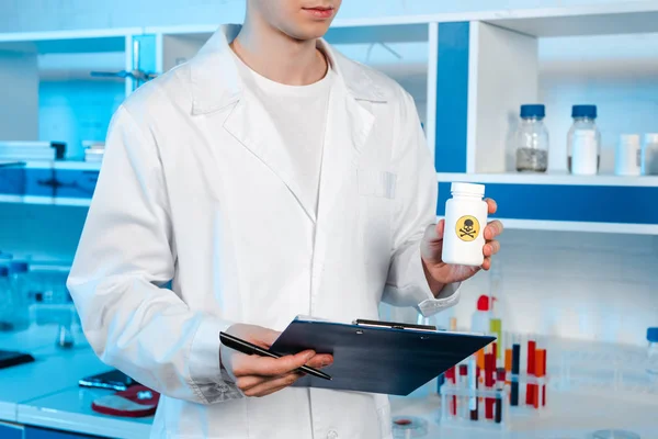 Обрезанный вид ученого, держащего планшет и бутылку с токсичным символом — стоковое фото