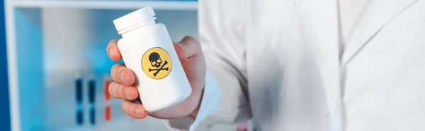 Tiro panorâmico de cientista segurando garrafa com símbolo tóxico — Fotografia de Stock