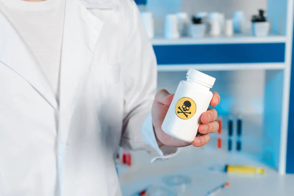 Vista recortada del científico sosteniendo la botella con símbolo tóxico - foto de stock