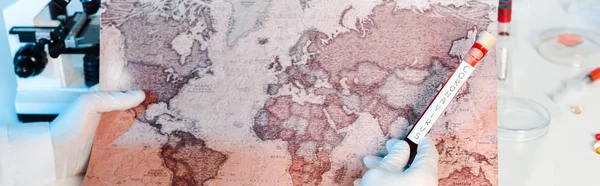 Tiro panorâmico de cientista segurando amostra com letras coronavírus perto do mapa — Fotografia de Stock