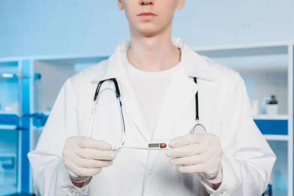 Cropped view of scientist in latex gloves holding digital thermometer — Stock Photo