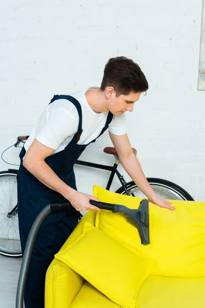 Hübsche Putzfrau in Overalls Sofa mit Staubsauger chemisch reinigen — Stockfoto