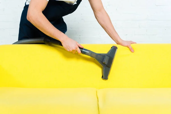 Cropped view of cleaner removing dust on sofa with vacuum cleaner — Stock Photo