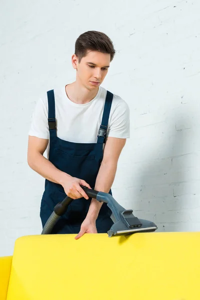 Beau nettoyeur enlever la poussière sur le canapé avec aspirateur — Photo de stock