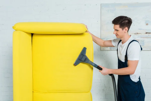 Perfil de limpador na limpeza a seco uniforme sofá moderno com aspirador de pó — Fotografia de Stock