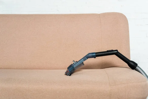 Aspirador de pó perto de sofá moderno na sala de estar — Fotografia de Stock