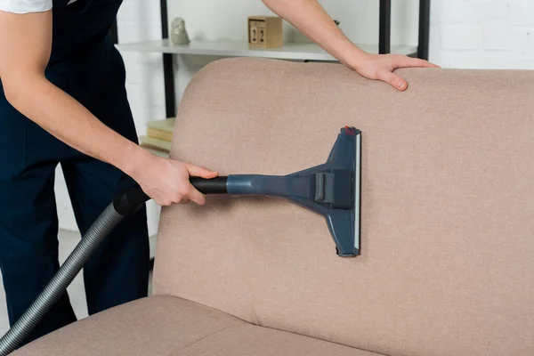 Cropped view of cleaner in uniform dry cleaning modern sofa with vacuum cleaner — Stock Photo