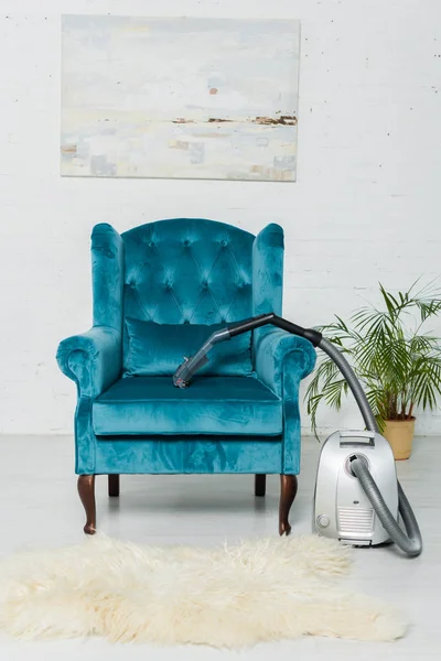 Vacuum cleaner on carpet near modern armchair in living room — Stock Photo