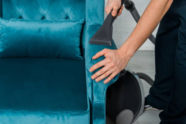 Vista recortada de hombre limpieza en seco moderno sillón con aspiradora - foto de stock