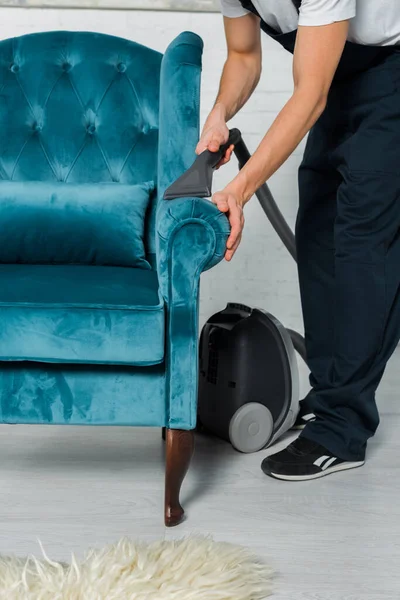 Vista recortada de limpiador en uniforme lavado en seco moderno sillón con aspiradora - foto de stock