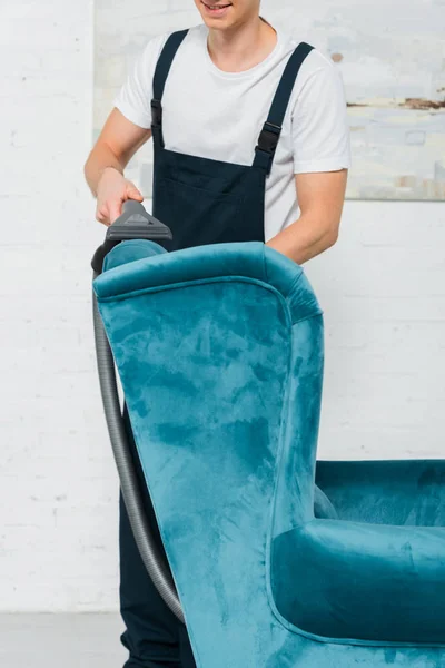 Vista recortada de limpiador feliz lavado sillón moderno con aspiradora - foto de stock