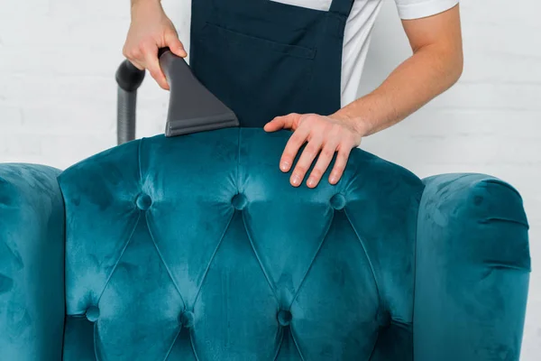 Vista recortada de limpiador tintorería azul moderno sillón con aspiradora - foto de stock