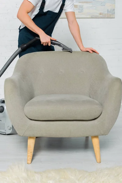 Vue recadrée du nettoyeur dans le fauteuil de nettoyage à sec uniforme avec aspirateur — Photo de stock