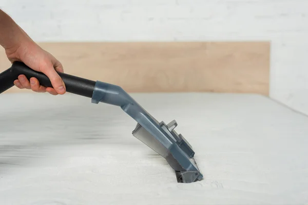 Cropped view of cleaner removing dust on mattress in bedroom with vacuum cleaner — Stock Photo