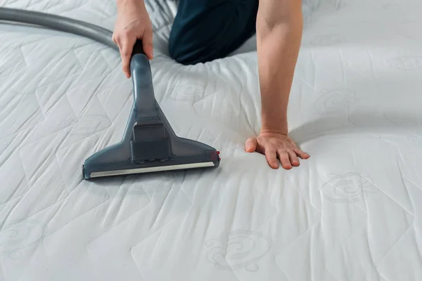 Cropped view of cleaner holding vacuum with handle while cleaning mattress — Stock Photo