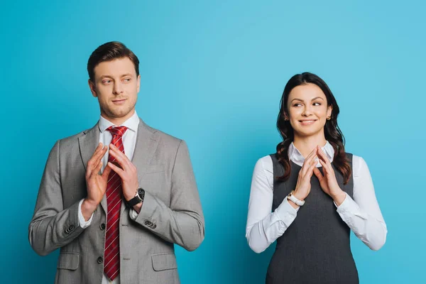 Souriant, rusé homme d'affaires et femme d'affaires tenant les doigts joints sur fond bleu — Photo de stock