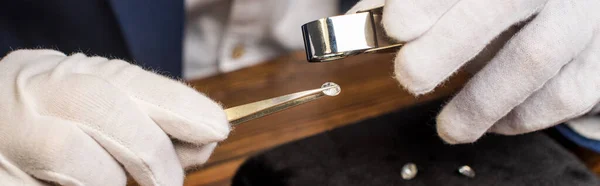 Nahaufnahme des Schmuckgutachters in Handschuhen mit Edelstein in der Zange und Lupe am Tisch, Panoramaaufnahme — Stockfoto