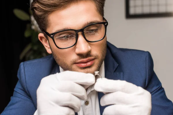 Concentration sélective du bel évaluateur de bijoux en gants tenant la bague avec la pierre précieuse dans l'atelier — Photo de stock