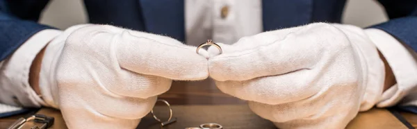 Ausgeschnittene Ansicht des Schmuckgutachters mit Schmuckring in der Nähe der Tafel auf einem Tisch isoliert auf grau, Panoramaaufnahme — Stock Photo