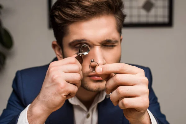 Jewelry appraiser with magnifying glass examining jewelry ring with gemstone in workshop — Stock Photo