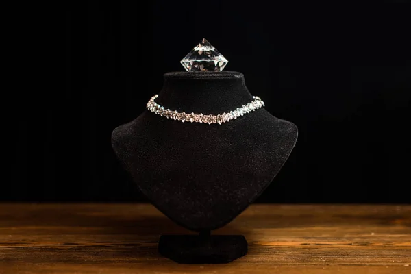 Collar soporte con collar y diamante en mesa de madera aislado en negro - foto de stock