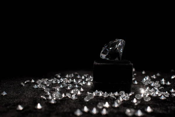 Diamond near gemstones on black velour isolated on black — Stock Photo