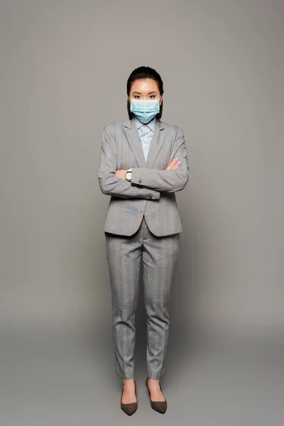 Junge Geschäftsfrau mit medizinischer Maske auf grauem Hintergrund — Stockfoto