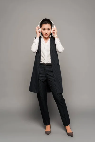 Giovane donna d'affari in cuffia su sfondo grigio — Foto stock
