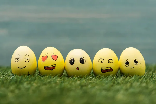 Huevos de Pascua con diferentes expresiones faciales en la hierba - foto de stock