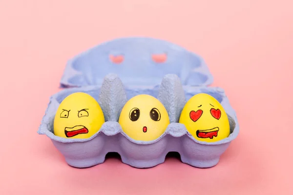 Selective focus of painted chicken eggs with facial expressions in egg tray on pink background, easter concept — Stock Photo