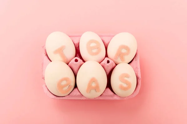 High angle view of chicken eggs with easter lettering in egg tray on pink — Stock Photo