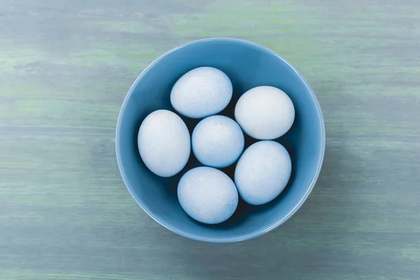 Top view of bowl with easter eggs on wooden background — Stock Photo