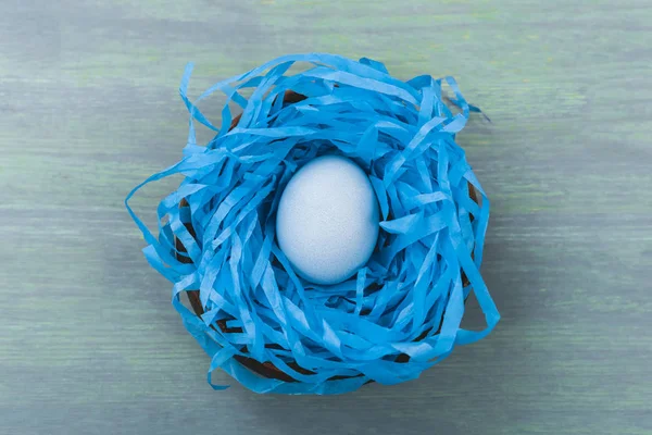 Top view of nest with painted chicken egg on wooden background, easter concept — Stock Photo