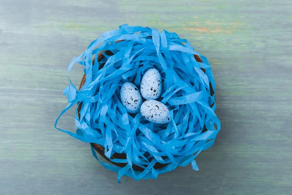 Top view of nest with painted quail egg on wooden background, easter concept — Stock Photo