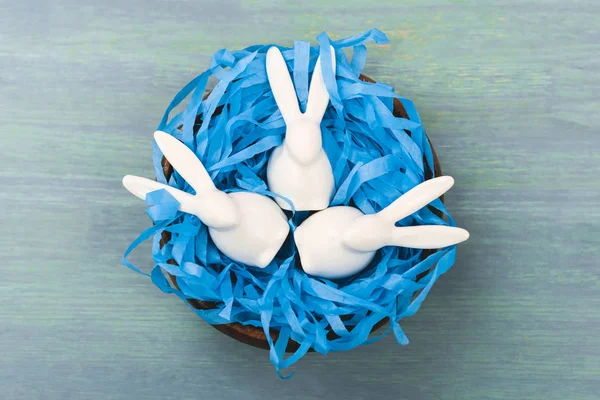 Top view of nest with decorative easter bunnies on wooden background — Stock Photo