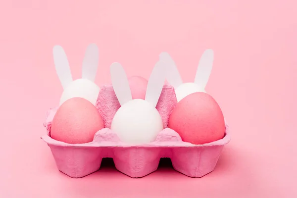 Conejos decorativos y huevos de Pascua sobre fondo rosa - foto de stock