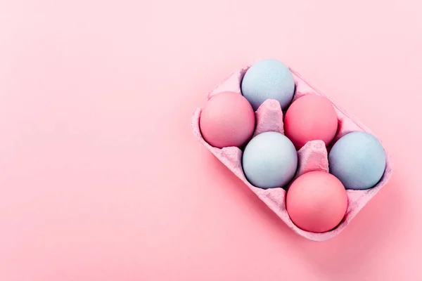 Vue grand angle des œufs de Pâques colorés dans le plateau d'œufs sur fond rose — Photo de stock