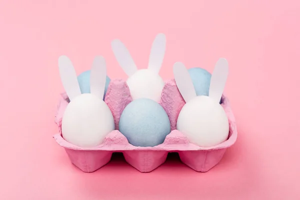 Conejos decorativos y coloridos huevos de Pascua sobre fondo rosa - foto de stock