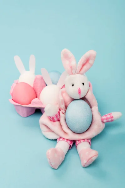 Egg tray with painted chicken eggs and decorative bunnies on blue background, easter concept — Stock Photo