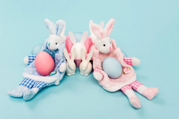 Painted chicken eggs and decorative easter bunnies on blue background — Stock Photo