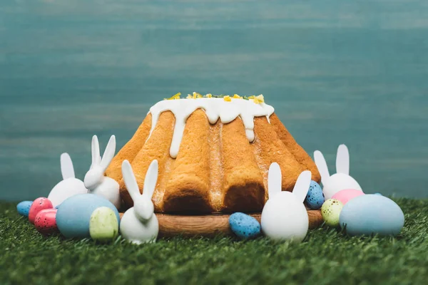 Pan de Pascua con huevos coloridos y conejitos decorativos en la hierba - foto de stock