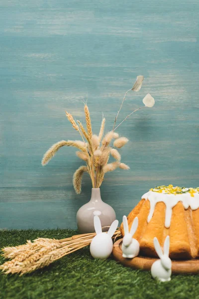 Пасхальный торт с декоративными кроликами и вазой с ивой и пшеницей на траве — стоковое фото