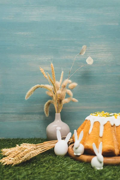 Bolo de Páscoa com coelhos decorativos e vaso com salgueiro e trigo na grama — Stock Photo