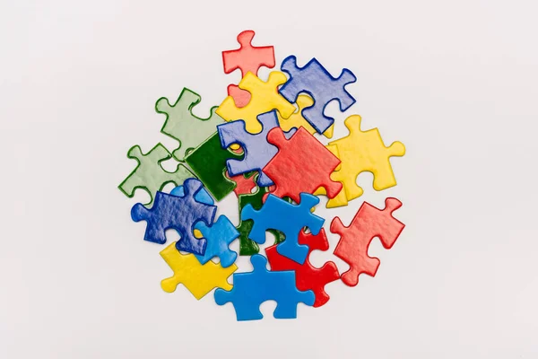 Vista superior de brillantes piezas multicolores de rompecabezas aislado en blanco, concepto de autismo - foto de stock