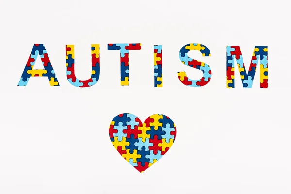 Vista dall'alto del cuore puzzle e Autismo lettering isolato su bianco — Foto stock