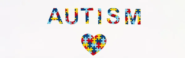 Vista superior do coração de quebra-cabeça um autismo lettering isolado em branco, tiro panorâmico — Fotografia de Stock