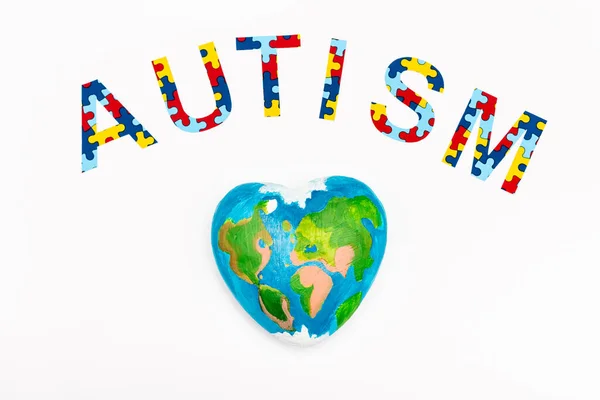 Vista superior de letras de quebra-cabeça de autismo e globo isolado em branco — Fotografia de Stock