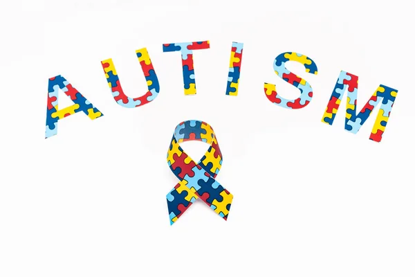 Vista de alto ângulo de letras de quebra-cabeça de autismo e fita de consciência isolada em branco — Fotografia de Stock