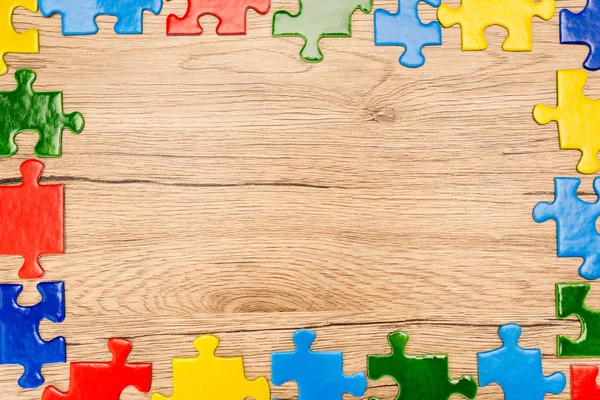 Vista superior de peças multicoloridas brilhantes de quebra-cabeça em fundo de madeira, conceito de autismo — Fotografia de Stock